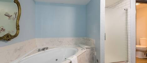 A bathroom with a large bathtub, a shower, and a toilet.