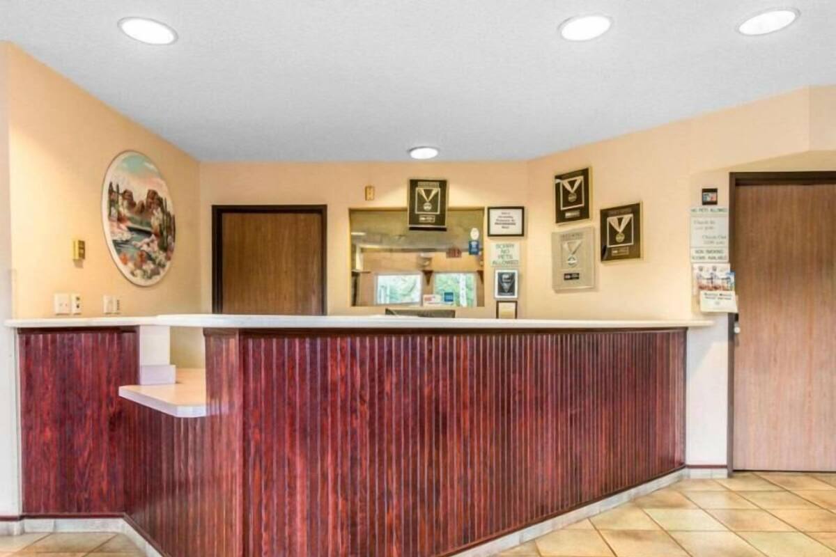 Un mostrador de recepción con detalles de madera, premios enmarcados en la pared y suelo de baldosas.