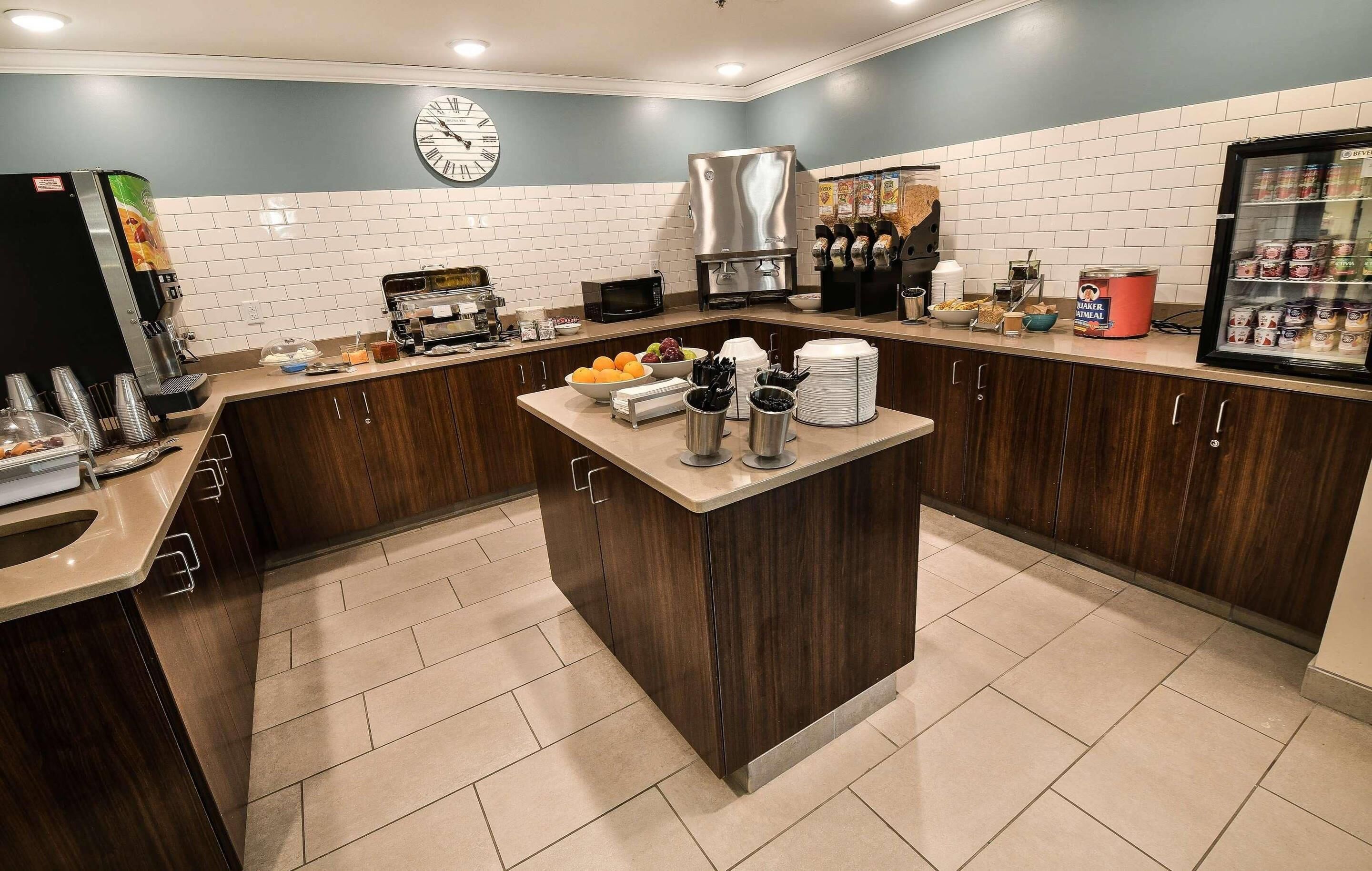 Une cuisine moderne dotée d’un îlot central, d’une machine à café et d’un réfrigérateur rempli de boissons.