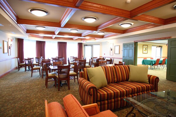 A hotel lobby with a striped sofa, wooden chairs, and tables. - Country Inn & Suites by Radisson, Grand Forks, ND (Grand Forks)