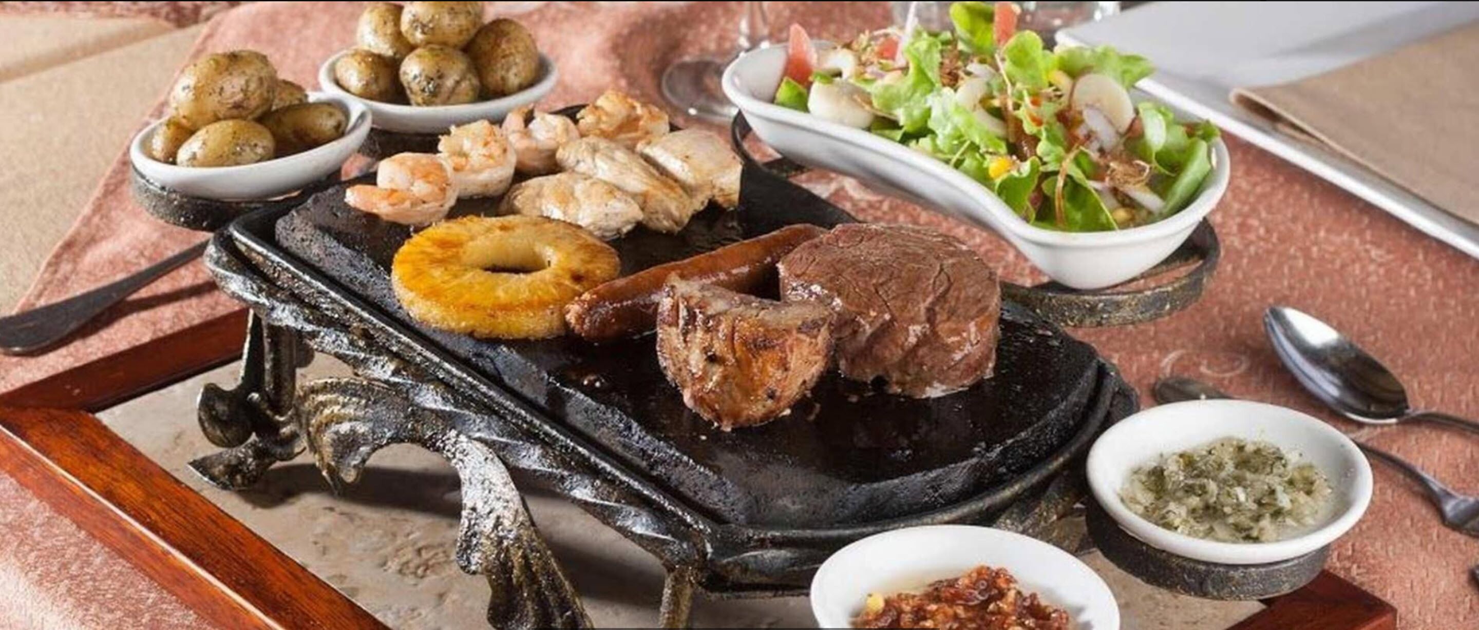 A variety of grilled meats, seafood, and a salad on a table.