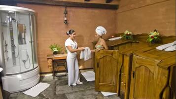 A spa room with a steam shower, wooden cabinets, and a small table with a plant.
