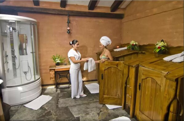 Un cuarto de spa con ducha de vapor, armarios de madera y una mesita con una planta.