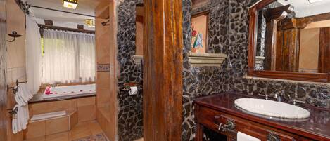 Un baño con pared de piedra, tocador de madera y bañera.