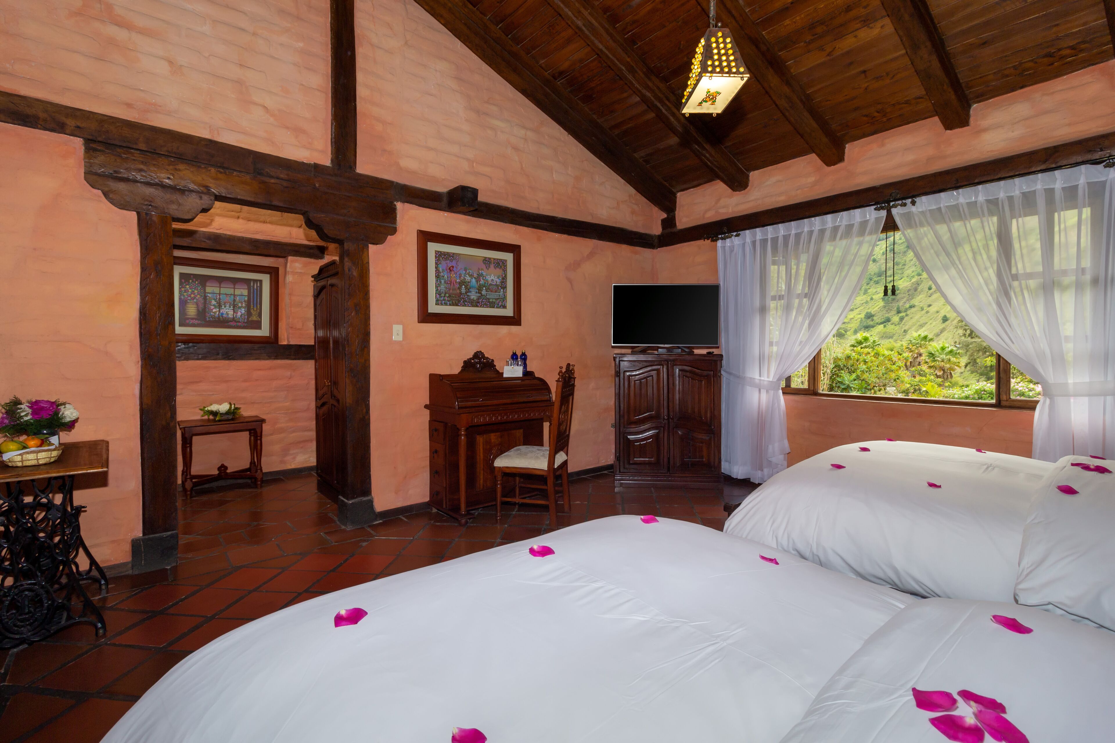 Un dormitorio con una cama grande, muebles de madera, un televisor y una ventana con vista a follaje.