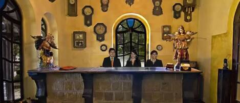 A reception area with a stone counter, multiple clocks, and a large arched window.