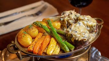 A dish of roasted vegetables and meat in a metal serving dish.