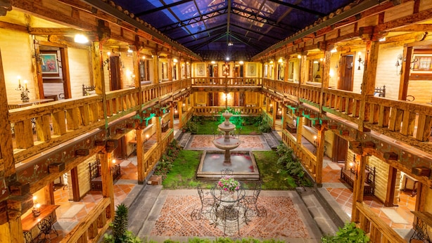 A spacious atrium with a central fountain, wooden railings, and a glass ceiling.