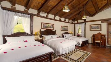 Habitación de hotel con dos camas grandes, cabeceros de madera, un escritorio de madera y un ventanal con cortinas.