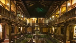 A courtyard with a central fountain, wooden balconies, and stone flooring.
