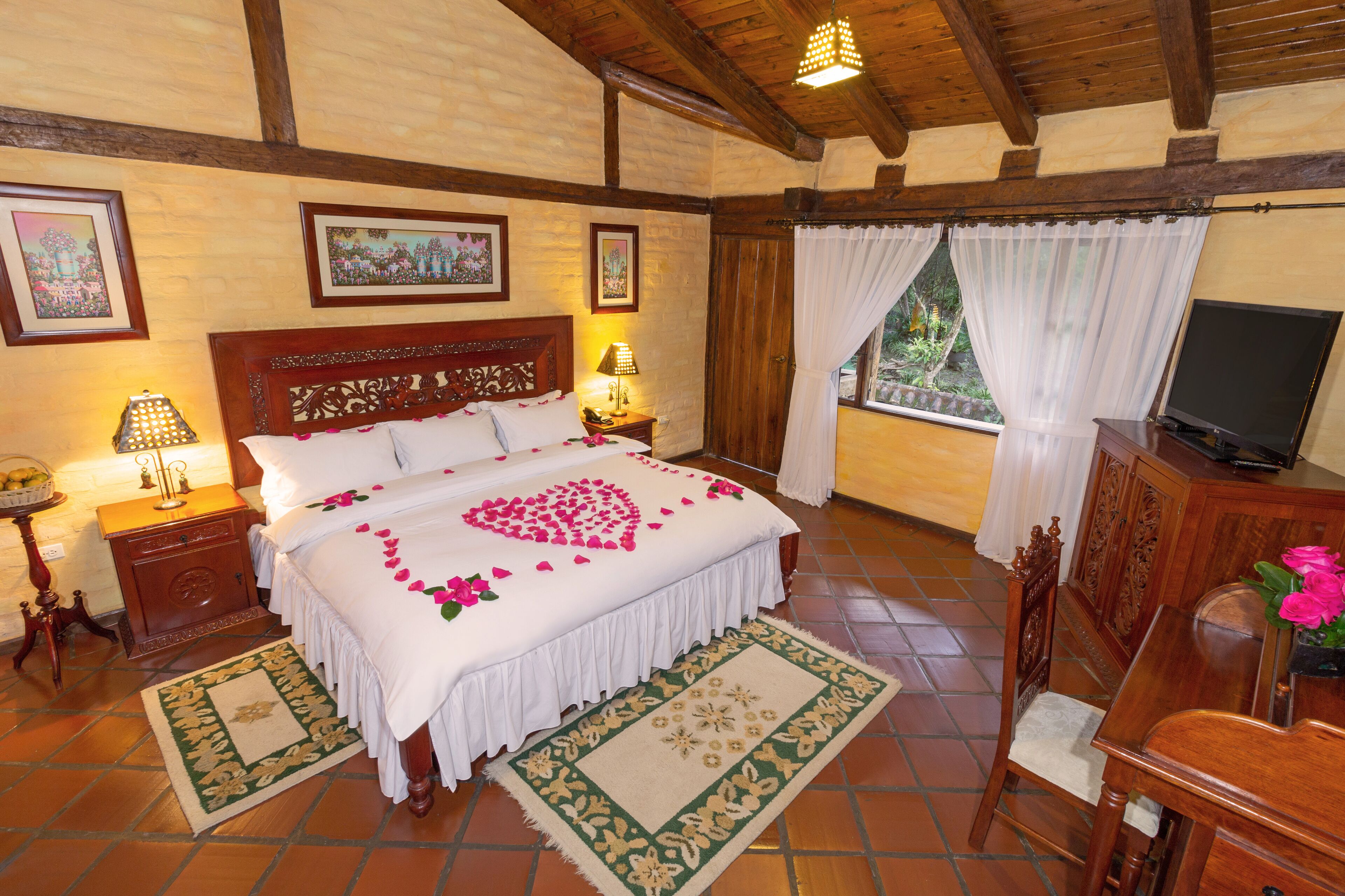 A bedroom with a wooden bed, a television, and a window with curtains.