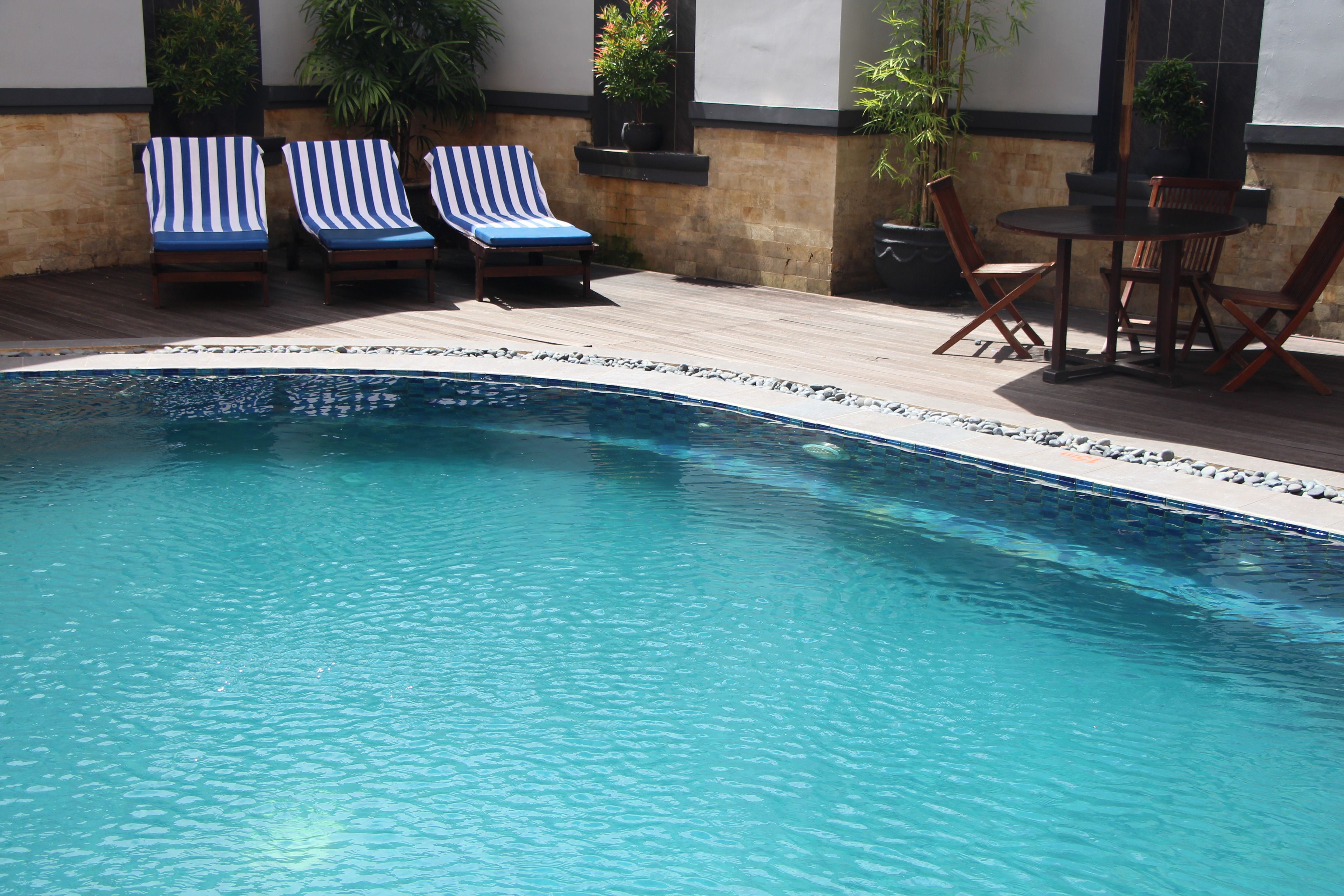 A swimming pool with lounge chairs and a table.