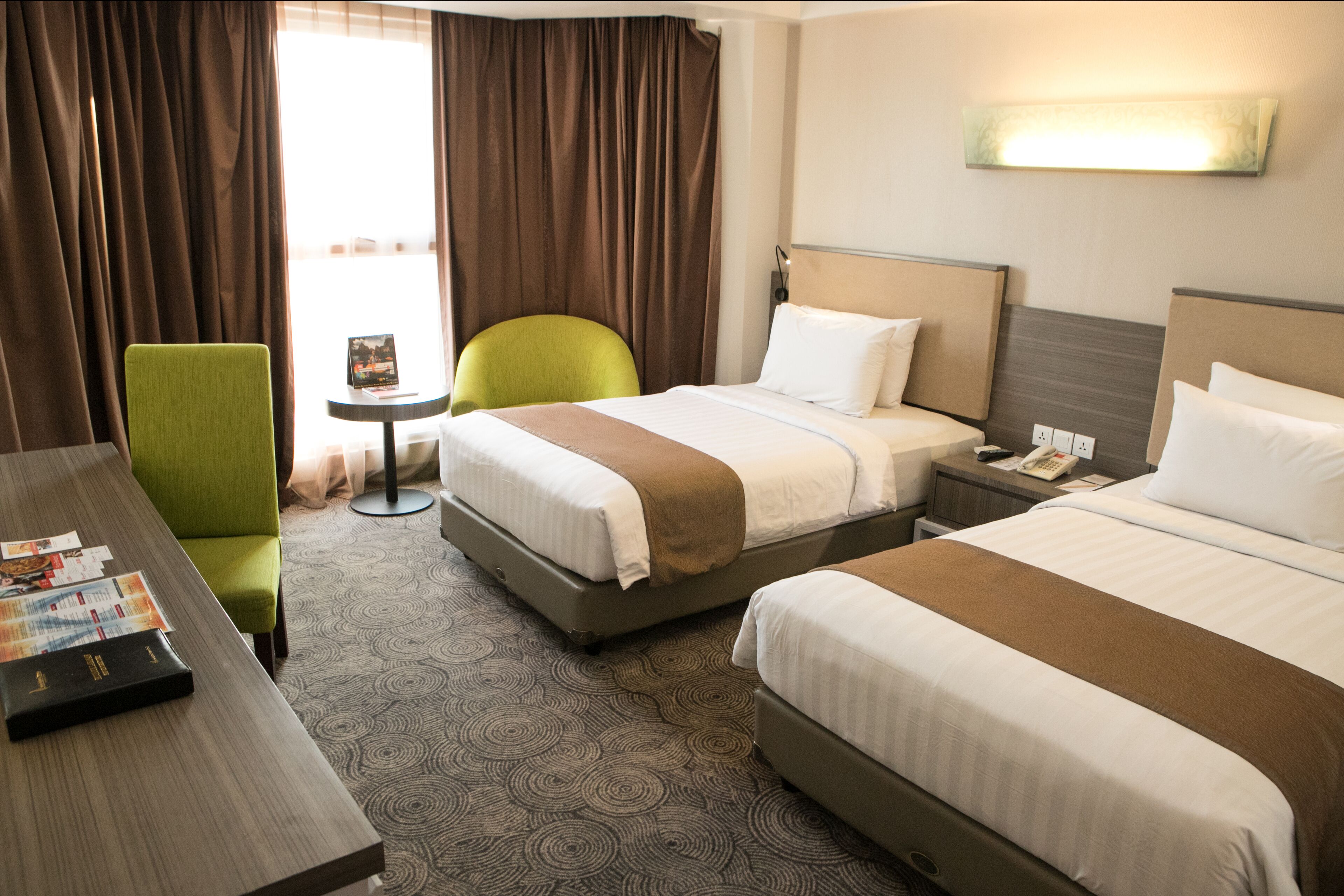 A hotel room with two beds, a desk, a chair, and a small table.