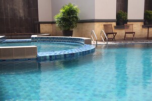 Una piscina al aire libre, sillones reclinables de piscina