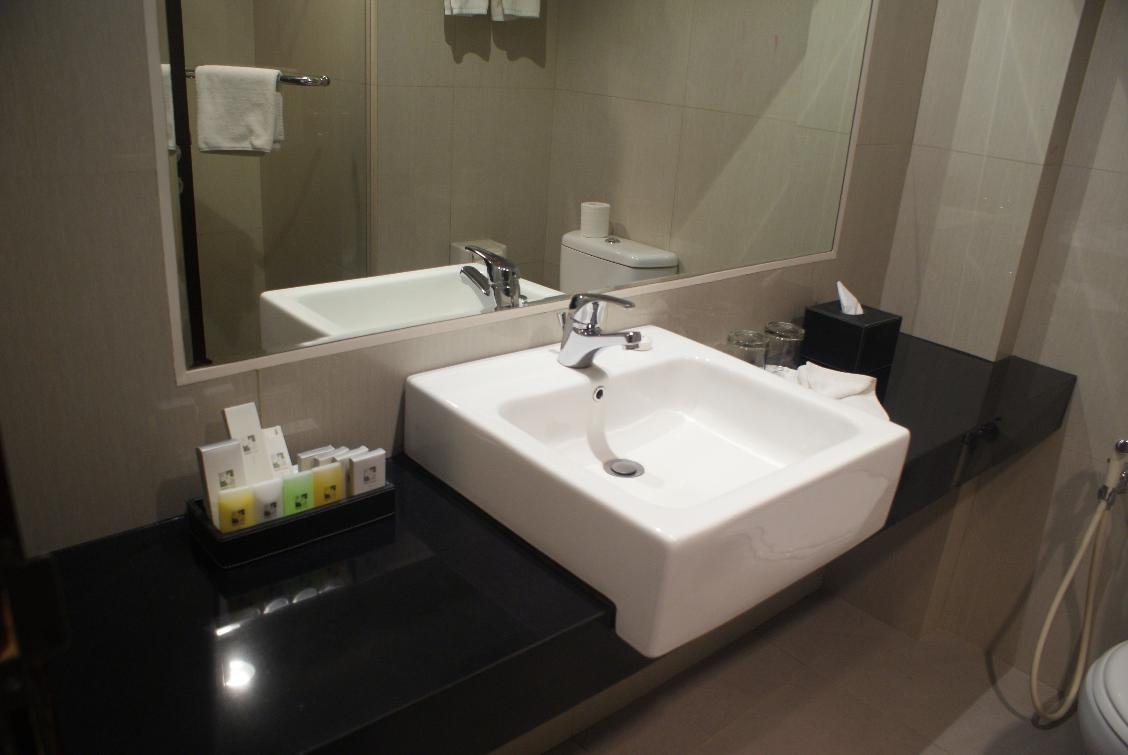 A modern bathroom with a white sink, mirror, and toilet.