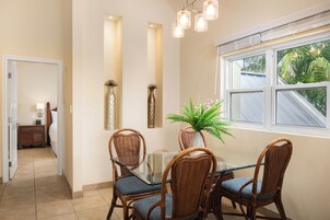 A dining area with a glass table, wicker chairs, and a potted plant.