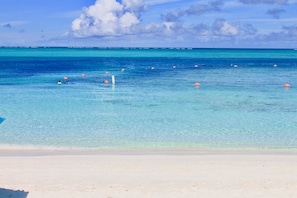 A beach with clear turquoise water, a sandy shore, and a few orange buoys. - Bungalows at Windsong on the Reef (Providenciales)