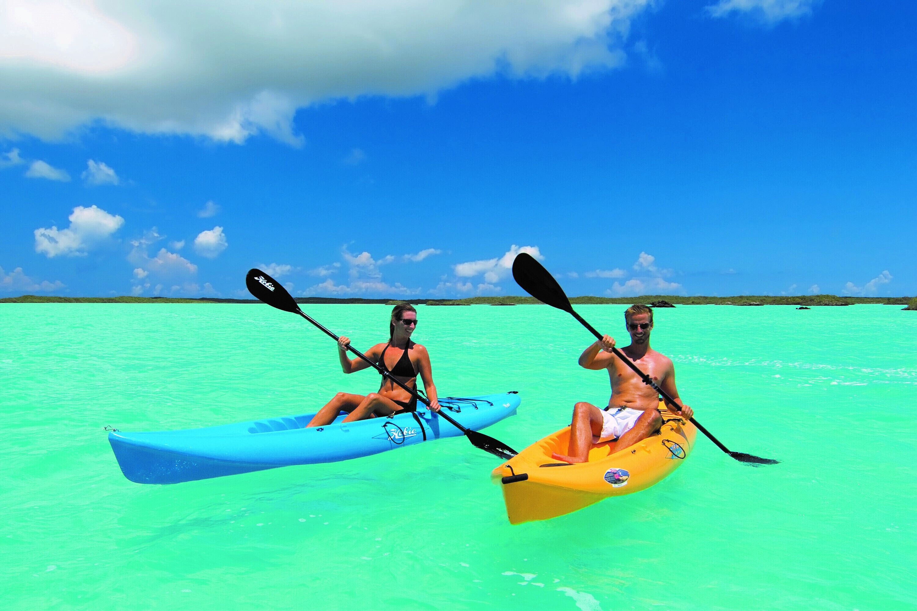 Twee mensen kajakken op turquoise water.