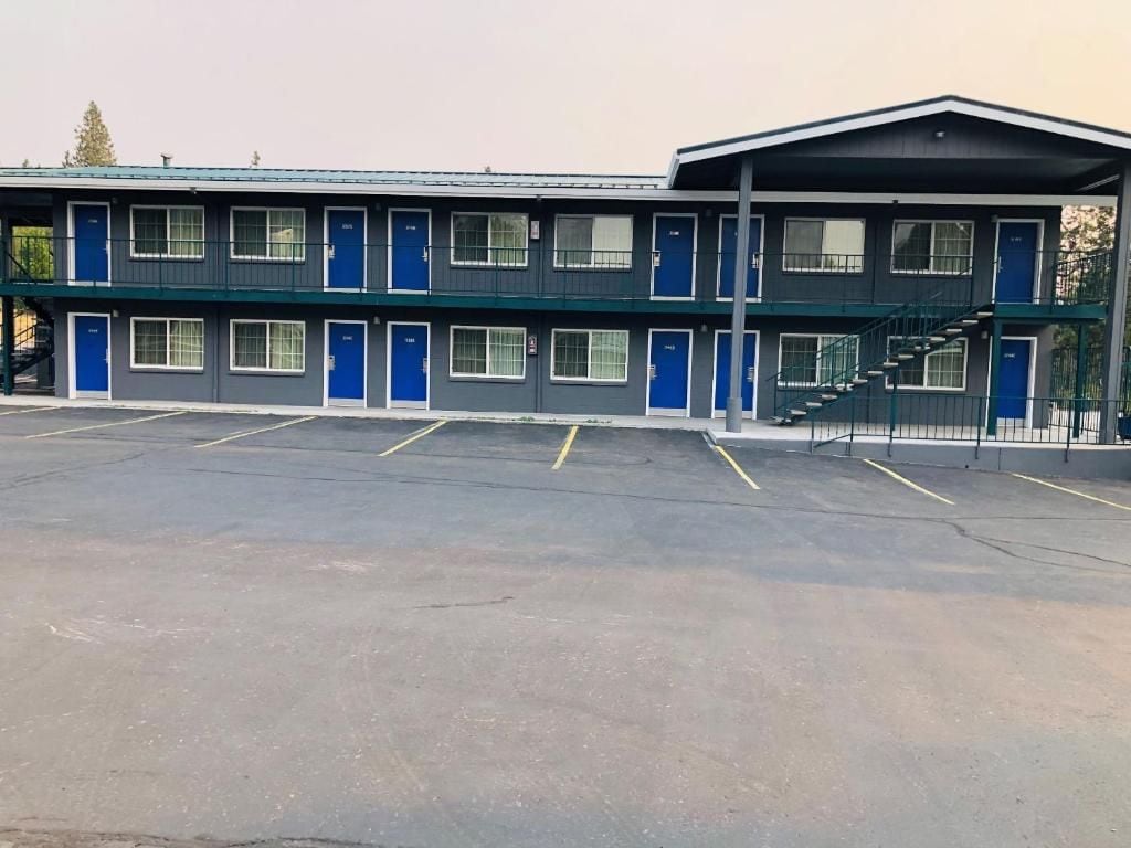 A motel with a two-story structure, multiple rooms with blue doors, and a parking lot.