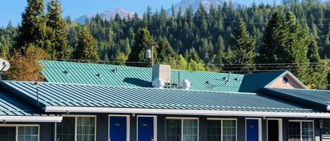 Un motel con techo verde, varias habitaciones y un estacionamiento.