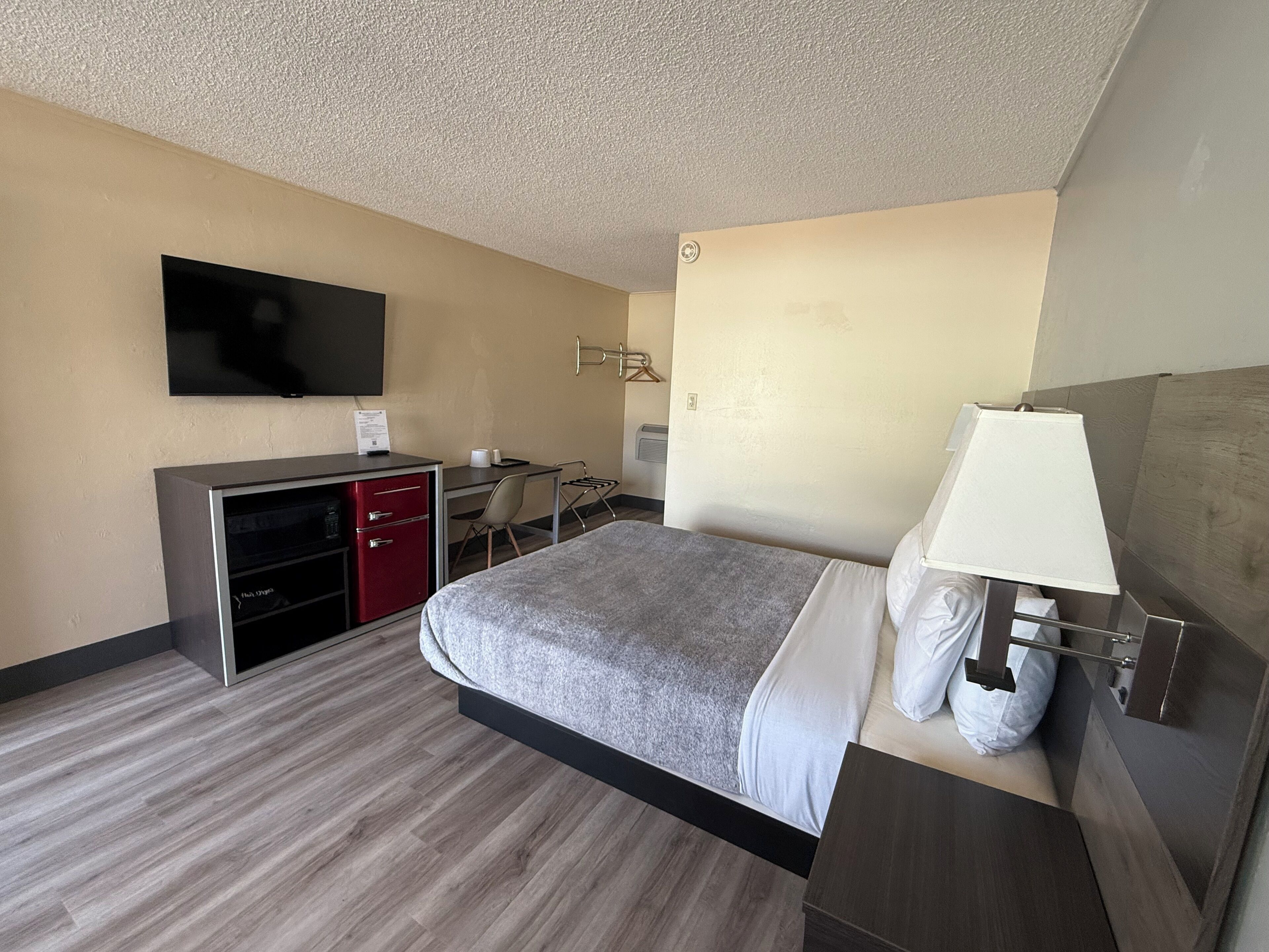 Une chambre d’hôtel équipée d’un lit, d’un bureau, d’une télévision et d’une armoire.