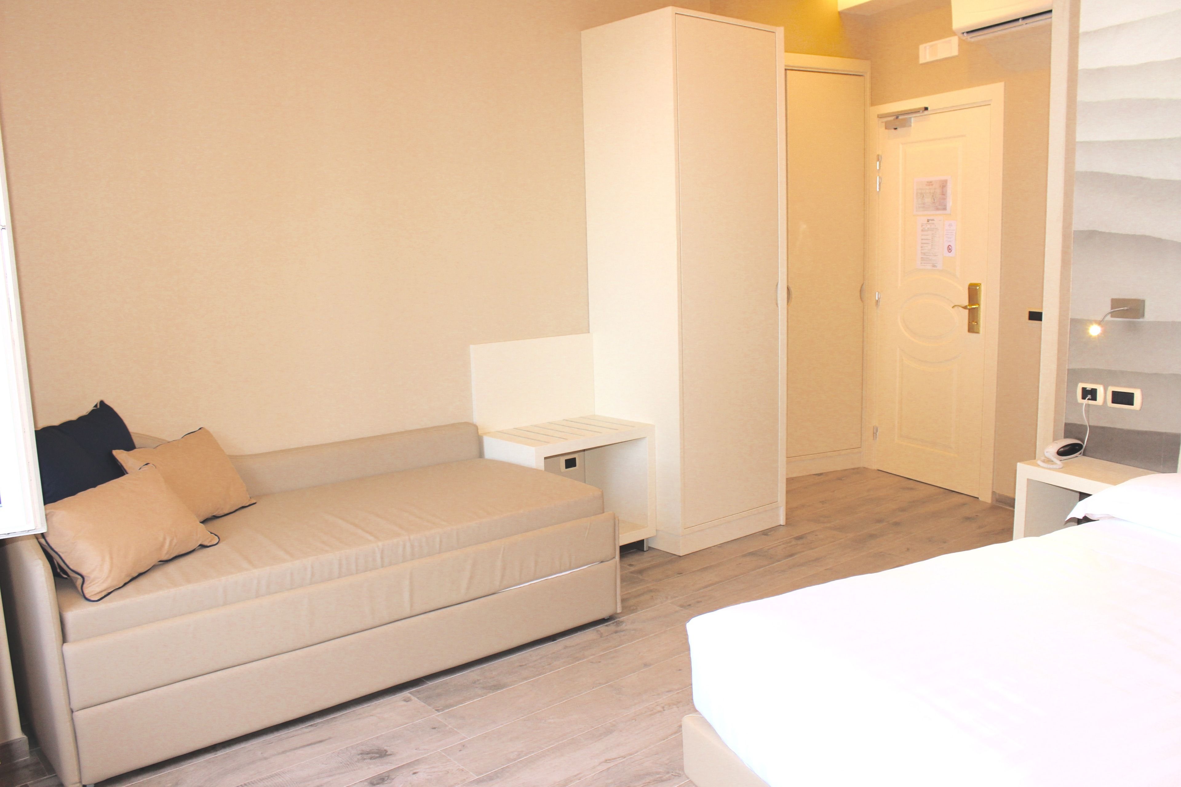 A bedroom with a bed, a sofa, a wardrobe, and a bedside table.