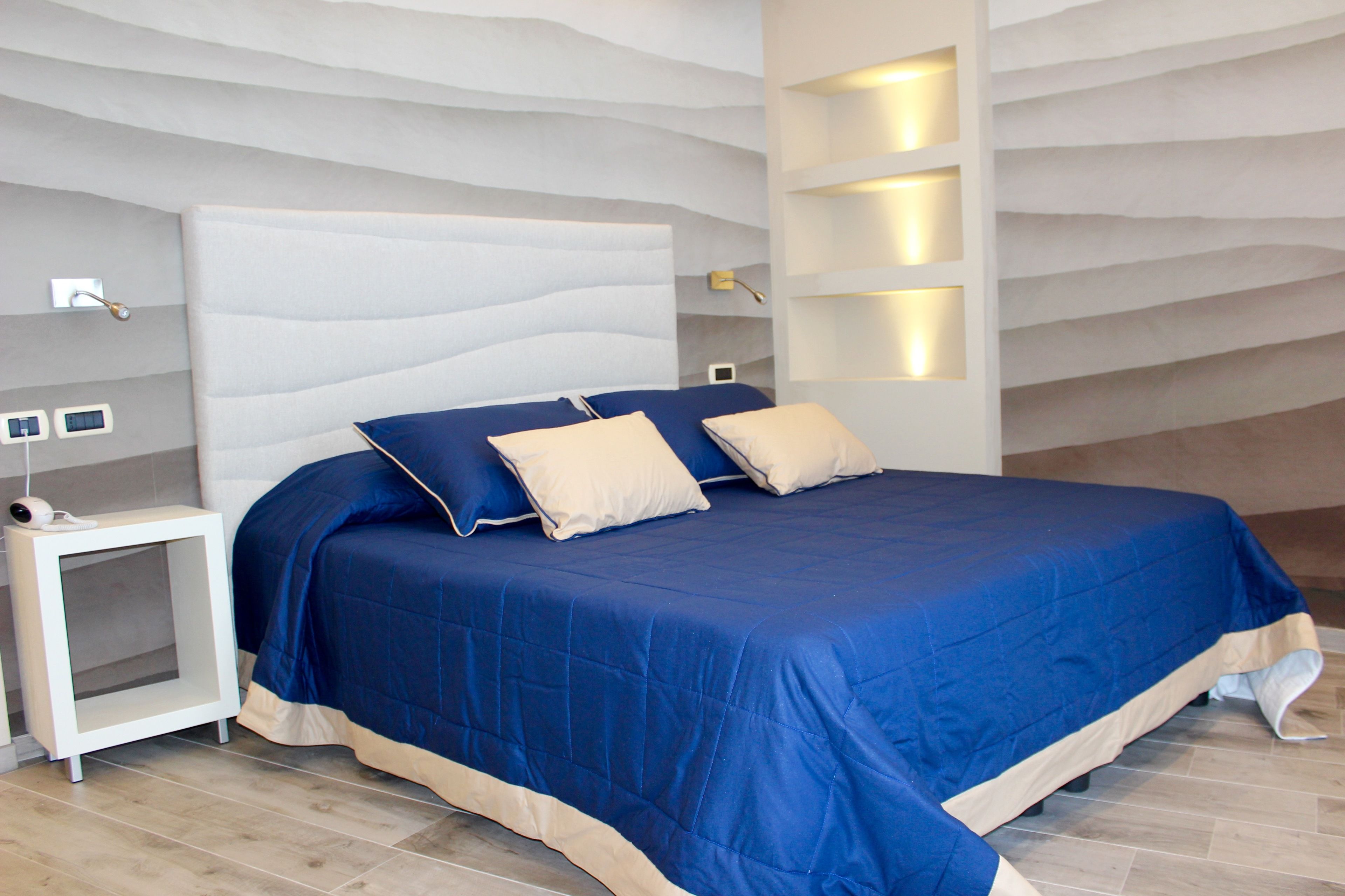 A modern bedroom with a large bed, a nightstand, and built-in lighting.