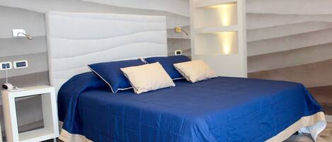 Un dormitorio moderno con una cama grande, una mesita de noche e iluminación empotrada.
