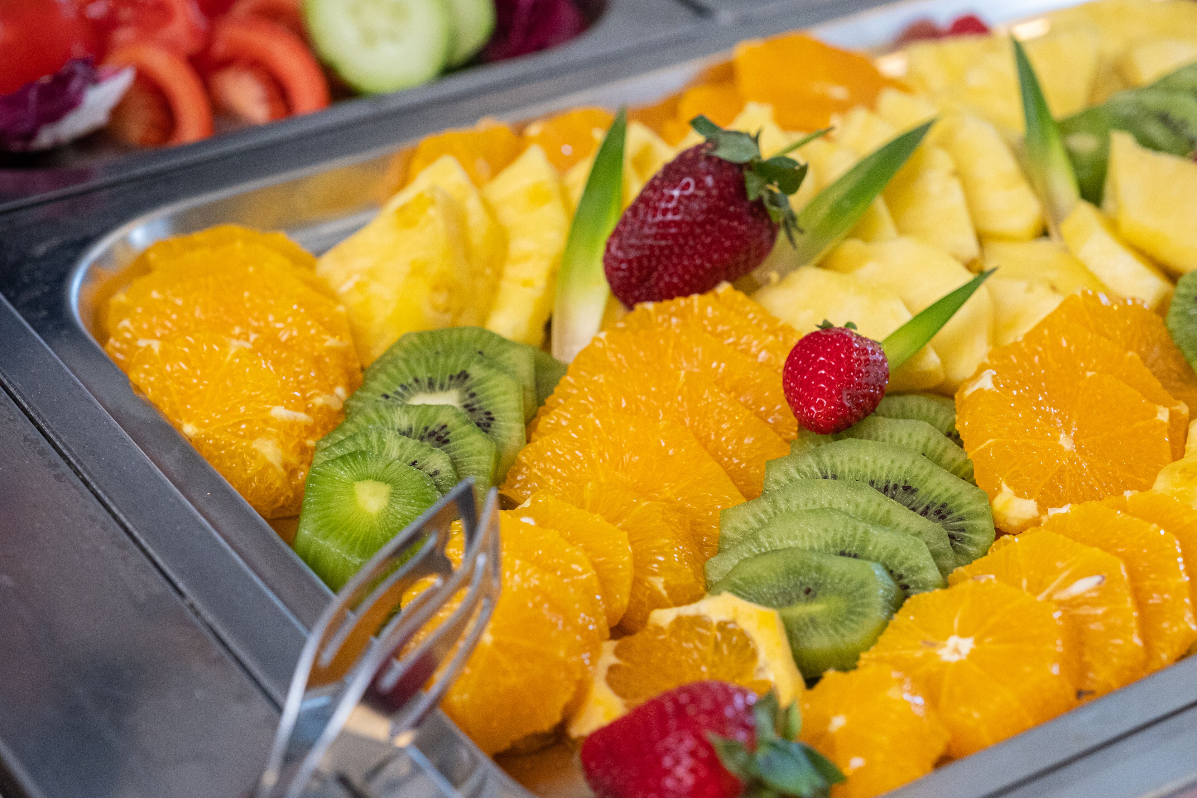 Buffet com variedade de frutas, incluindo laranjas, kiwis e morangos.