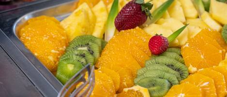 Buffet com variedade de frutas, incluindo laranjas, kiwis e morangos.