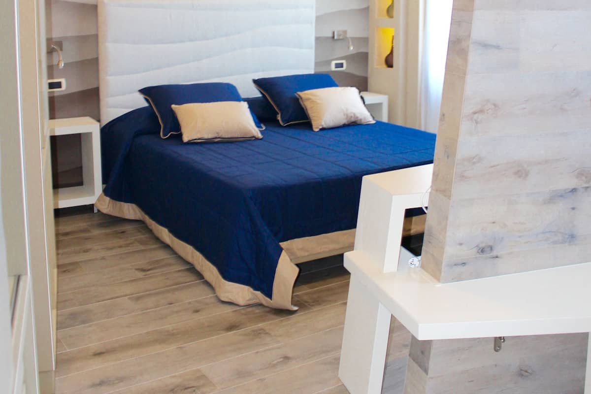 A modern bedroom with a large bed, bedside tables, and a built-in bench.