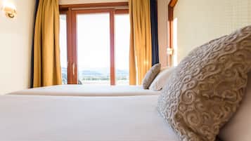 A hotel room with a large bed, a view of the outdoors, and curtains.