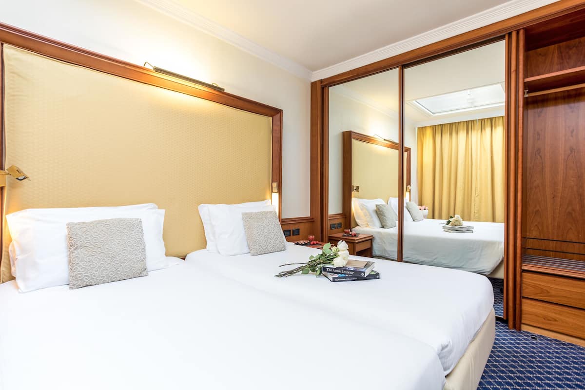 Une chambre d’hôtel avec deux lits, un grand miroir et une armoire.