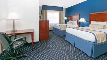 A hotel room with two beds, a desk, and a chair.