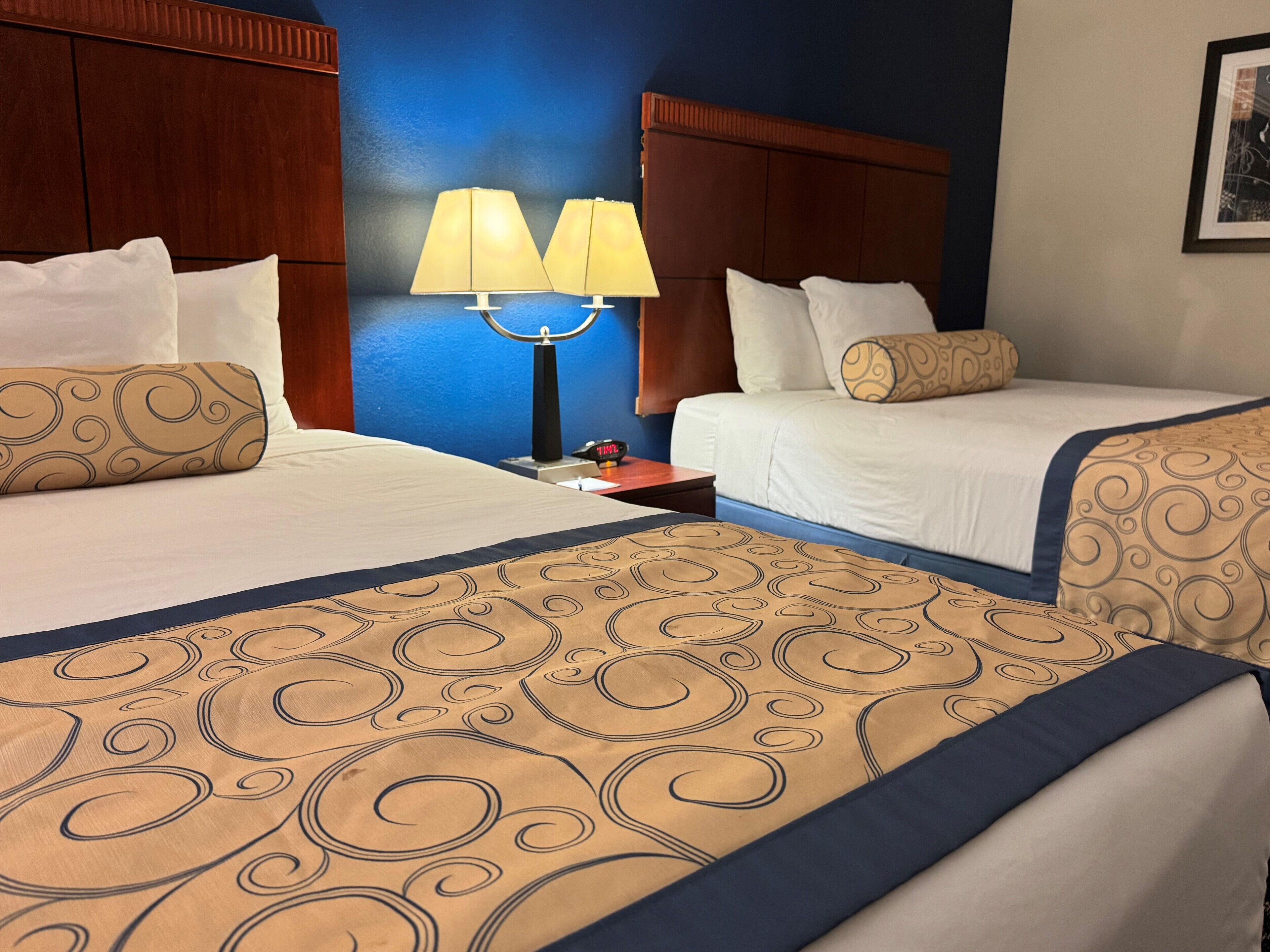 Ein Hotelzimmer mit zwei Betten, einem Nachttisch mit Lampe und einer blauen Wand.