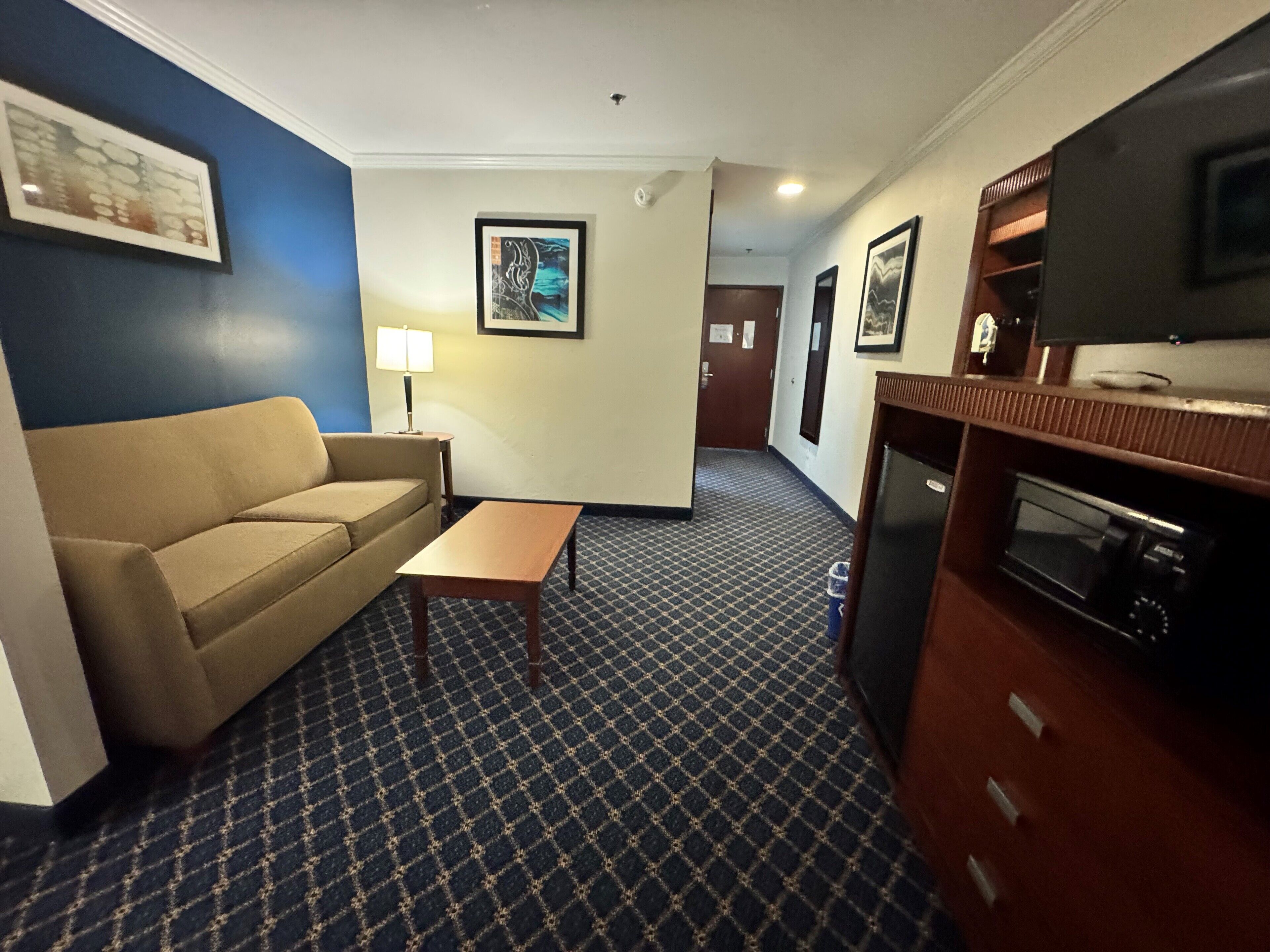 Una habitación de hotel con sofá, una mesita, microondas y televisión.