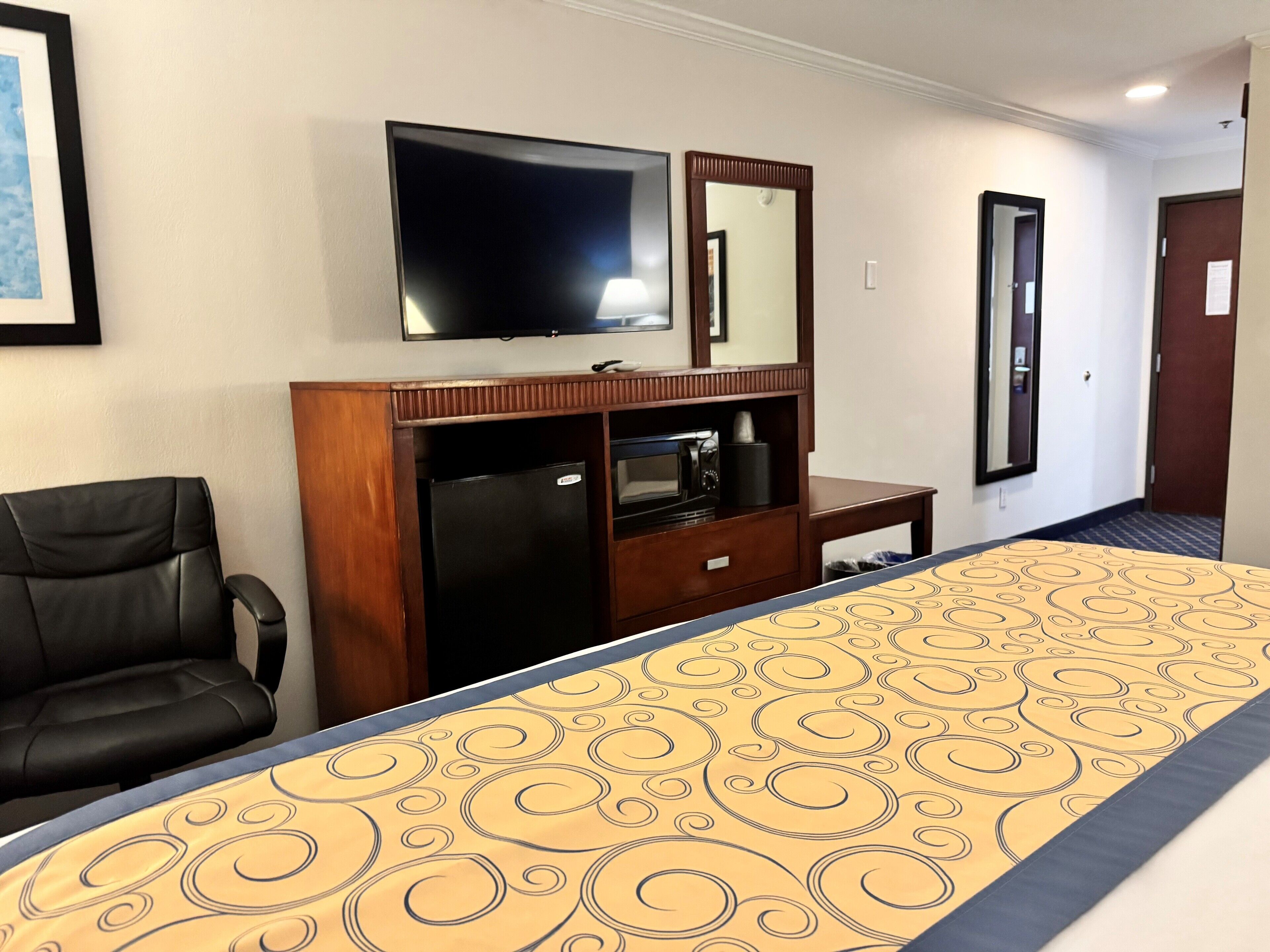 Une chambre d’hôtel équipée d’un lit, d’un bureau, d’une télévision, d’un réfrigérateur et d’une chaise.