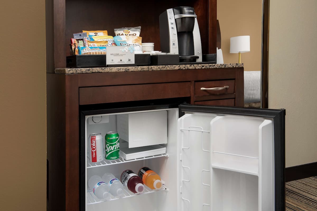 Eine Hotelminibar mit Kaffeemaschine, Snacks und Getränken.