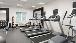 Une salle de sport équipée de tapis de course, d’haltères et de ballons d’exercice.
