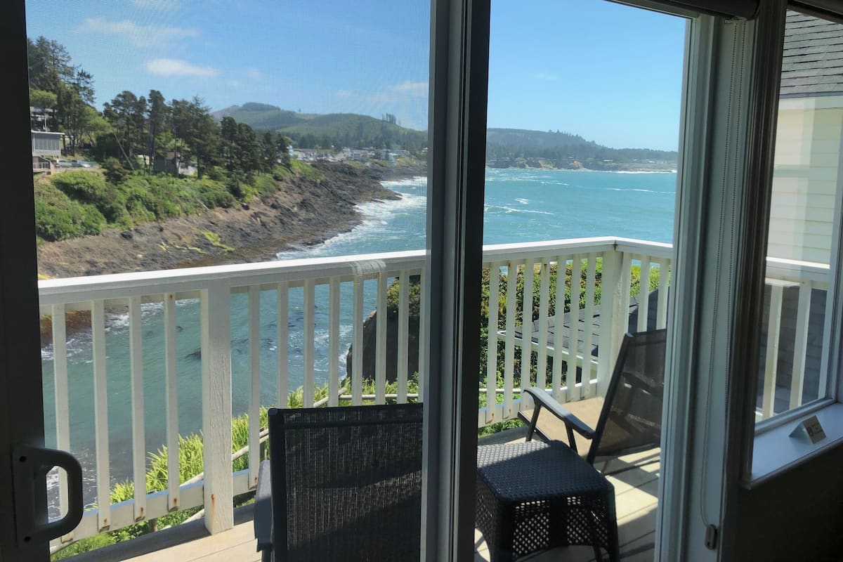 A balcony with a view of the ocean and a chair.