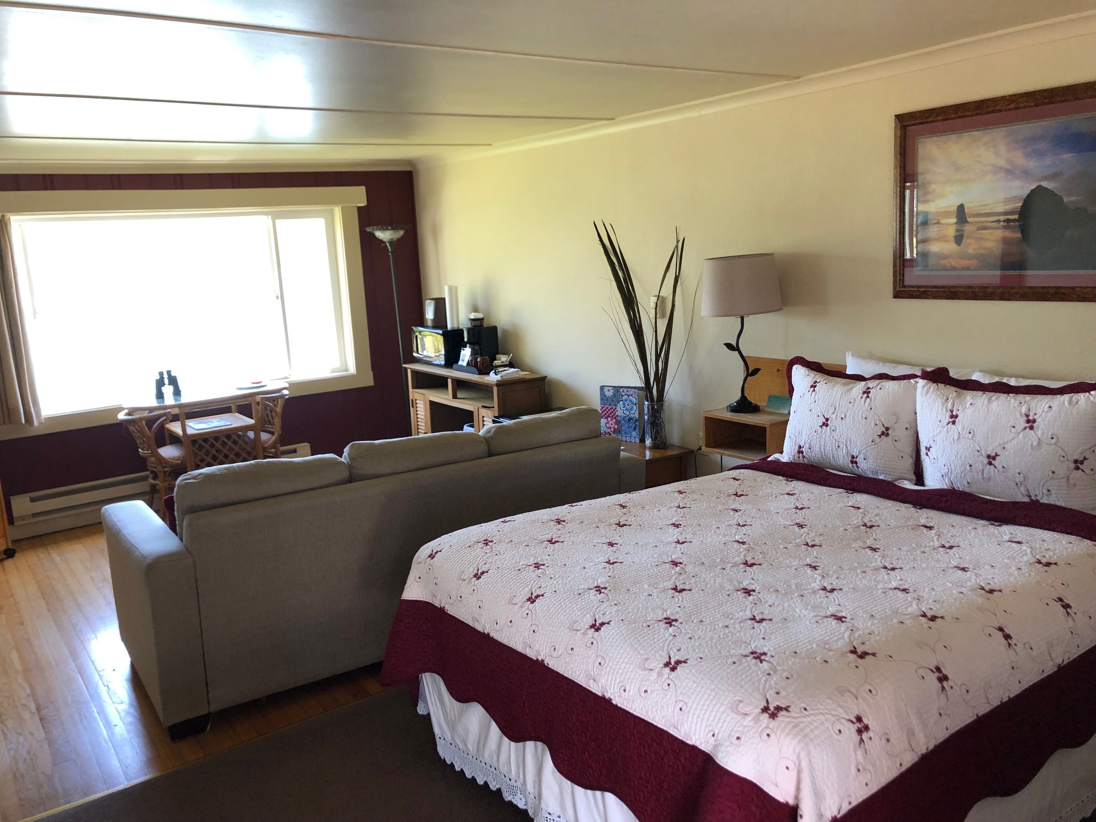 Une chambre d’hôtel avec un grand lit, un canapé, un bureau avec une lampe et une fenêtre avec des rideaux.