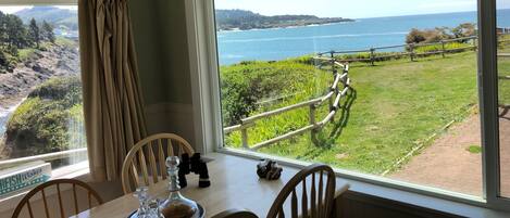 A dining area with a table, chairs, and a view of the sea and hills.