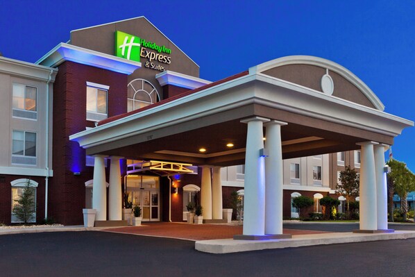 A Holiday Inn Express & Suites hotel with a covered entrance, brick facade, and a sign above the entrance.