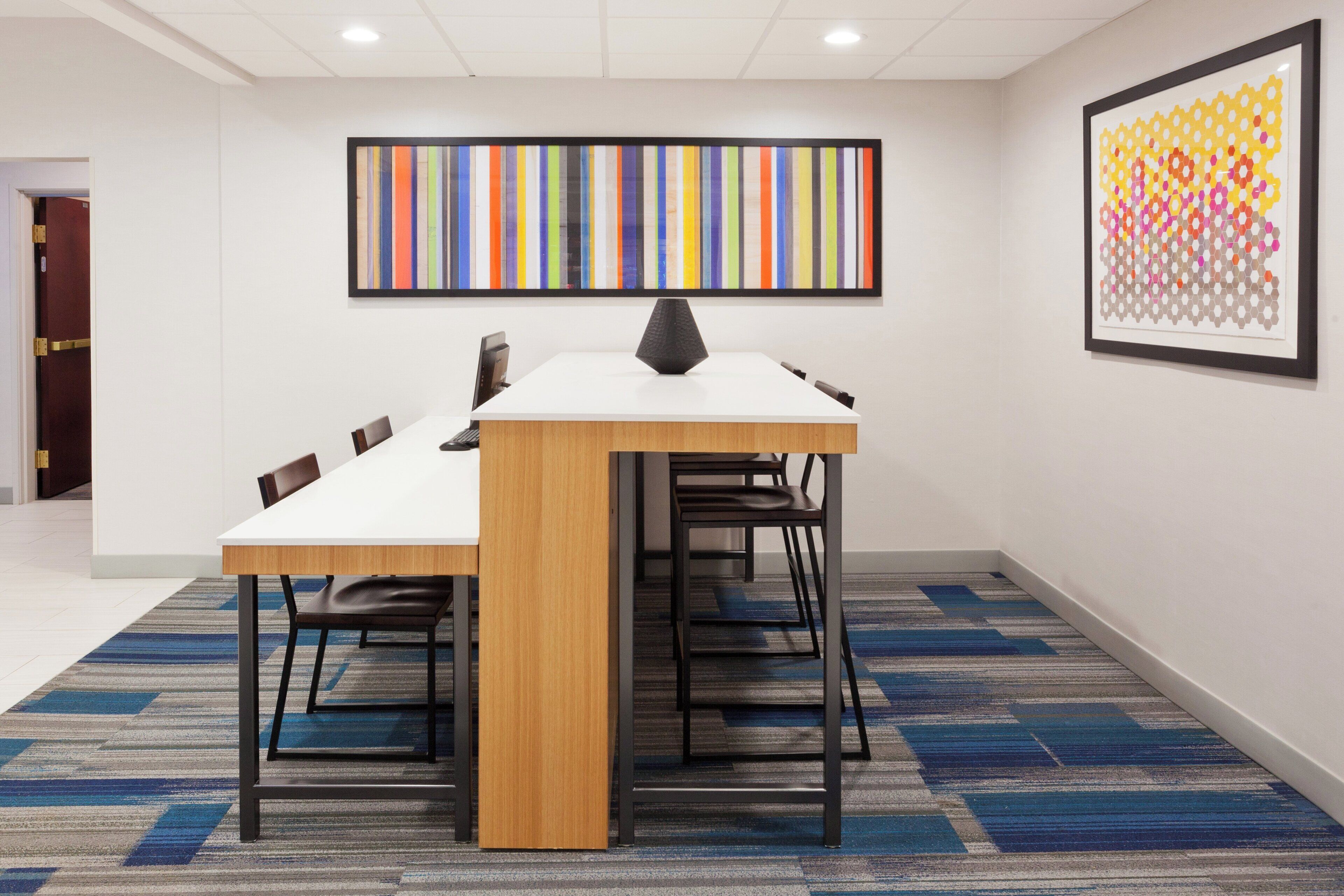 A conference room with a white table, black chairs, and a carpeted floor.