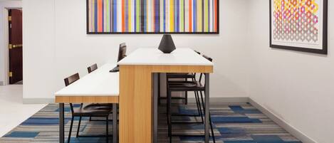 A conference room with a white table, black chairs, and a carpeted floor.