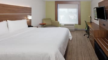 Una camera d'albergo con un letto grande, una scrivania con una sedia, una televisione e una finestra con persiane.