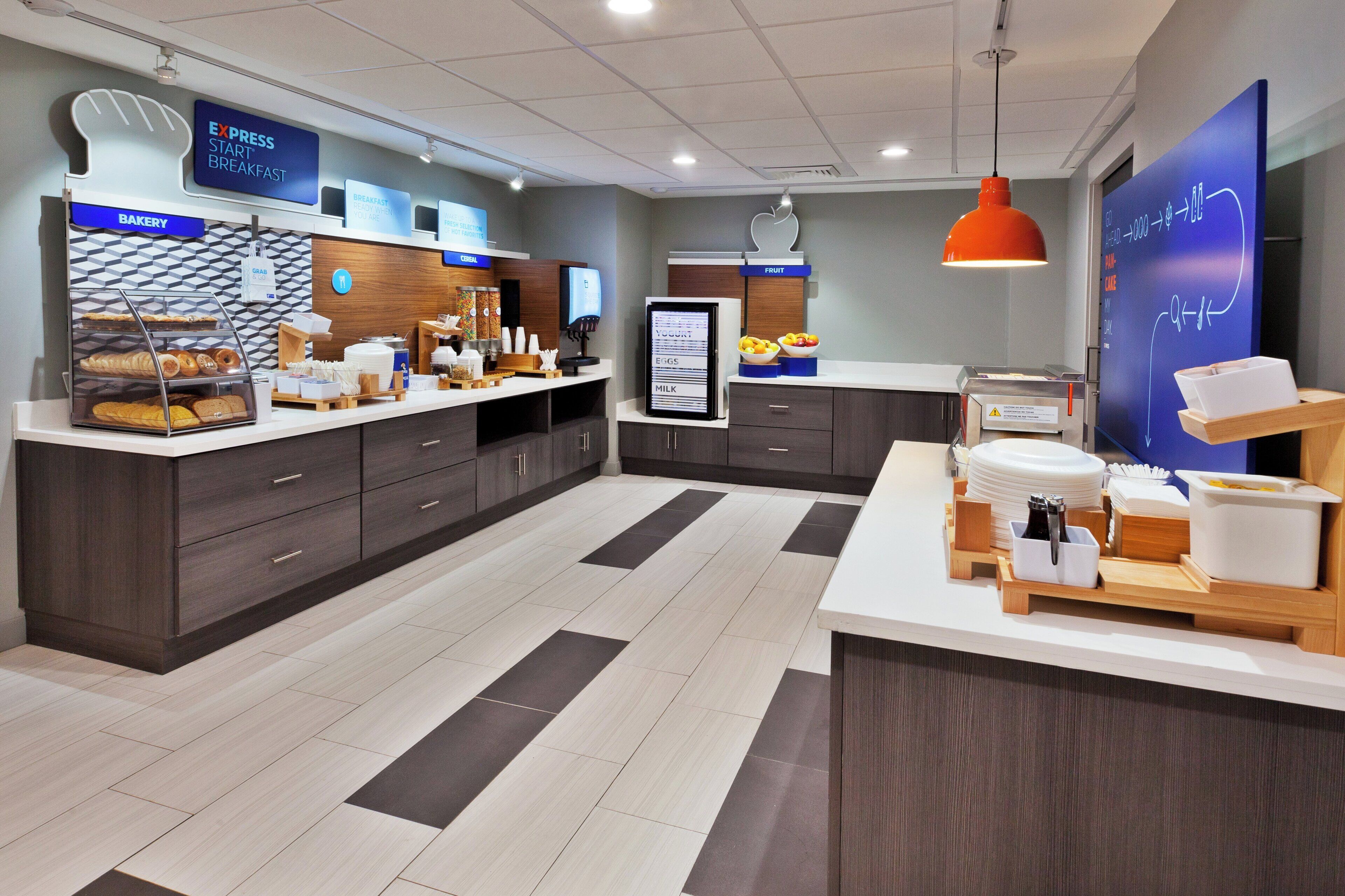 A breakfast area with a bakery display, cereal, and fruit options.
