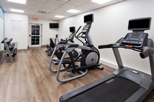 Un gimnasio con cintas de correr, elípticas y máquinas de pesas.