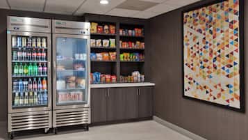 Un área de venta con dos dispensadores de bebidas y un estante con snacks.