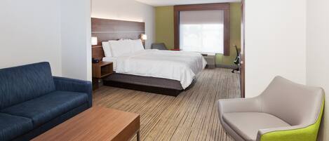Una habitación de hotel con una cama, un sofá azul, una mesa de centro de madera y un sillón verde.